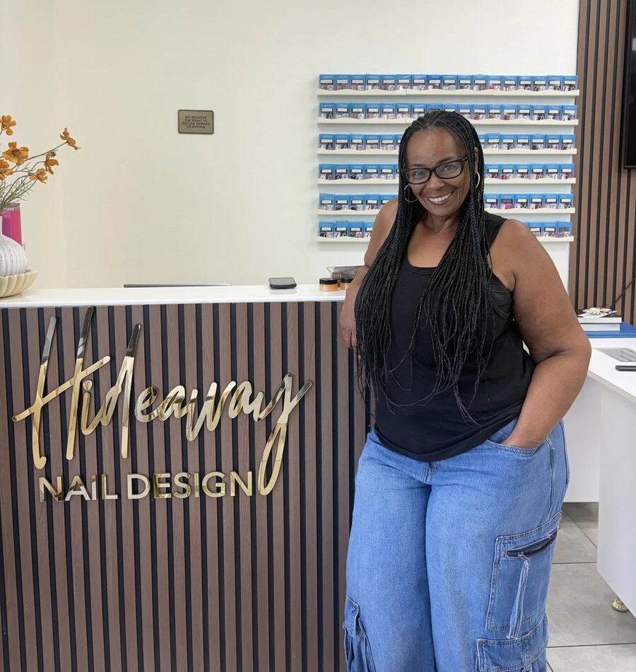 Tameisha Warner, owner of Hideaway Nail Design, smiling at the front desk