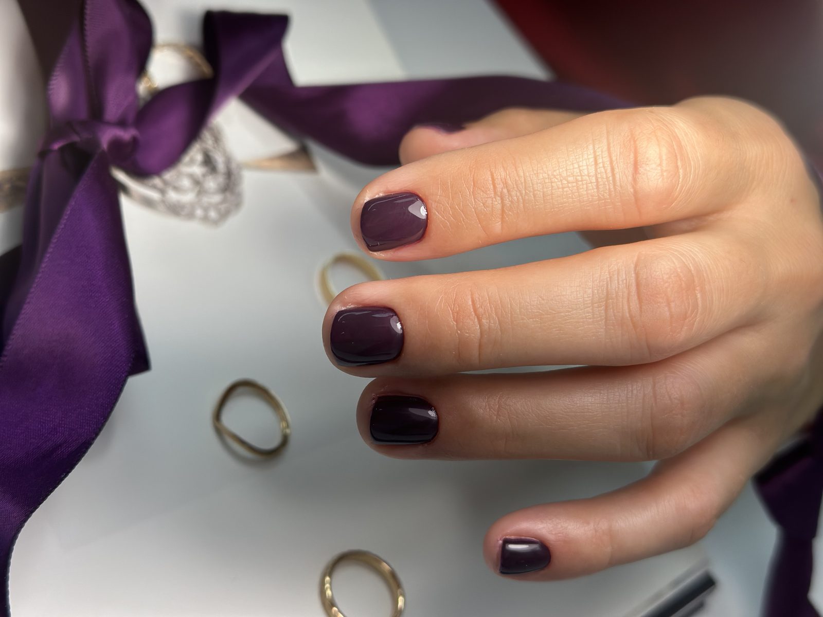 Plum gel manicure styled with ribbon at Hideaway Nail Design