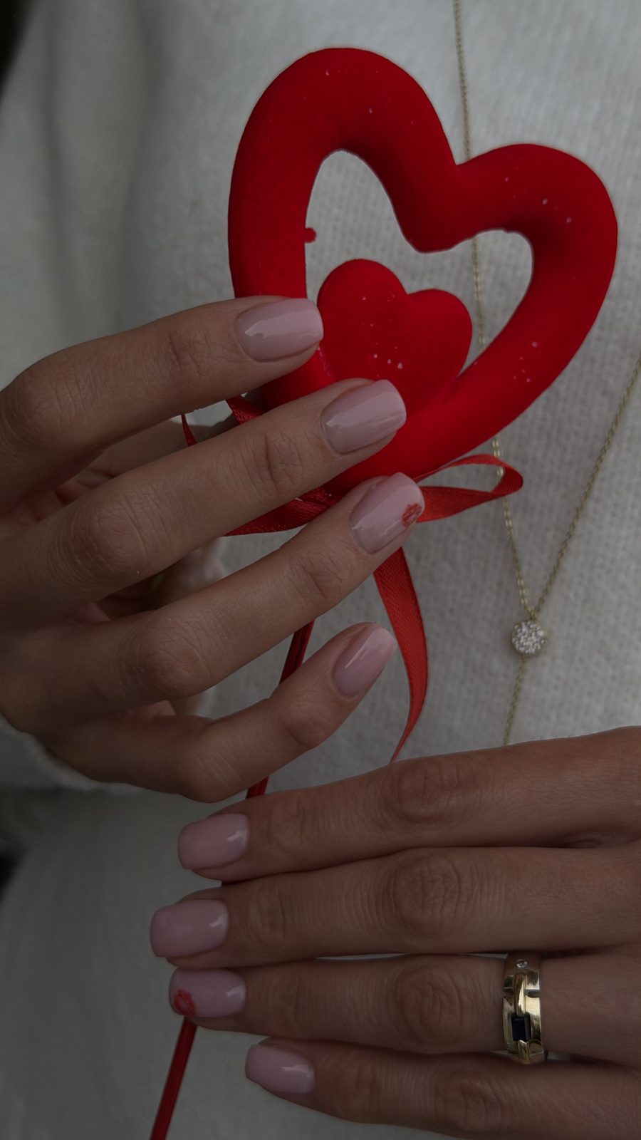 Soft pink manicure holding a red heart at Hideaway Nail Design